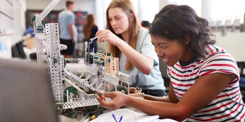 Two students sitting next to eachother and engaging in a building activity